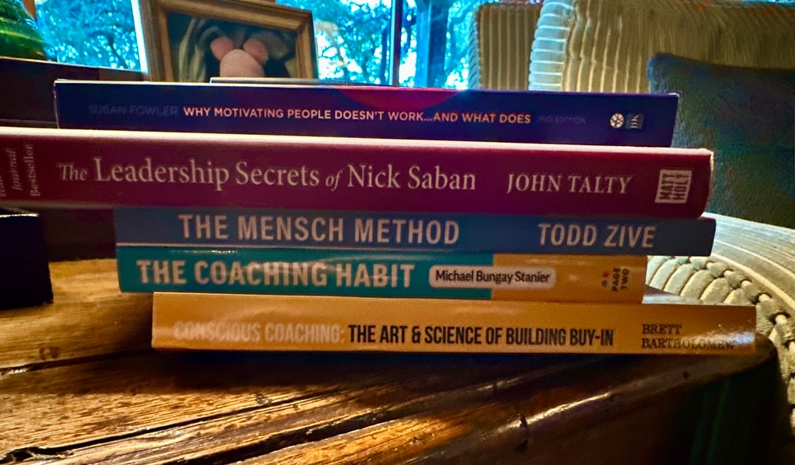 A stack of books on Gary Keller's Nightstand: Includes – WHY MOTIVATING PEOPLE DOESN'T WORK, The Leadership Secrets of Nick Saban, THE MENSCH METHOD, and CONSCIOUS COACHING: THE ART &amp; SCIENCE OF BUILDING BUY-IN.